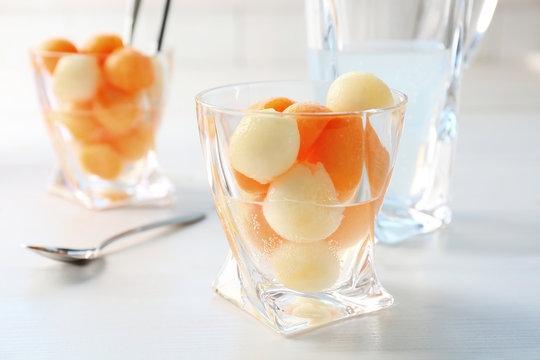 Glass of delicious cocktail with melon balls on table