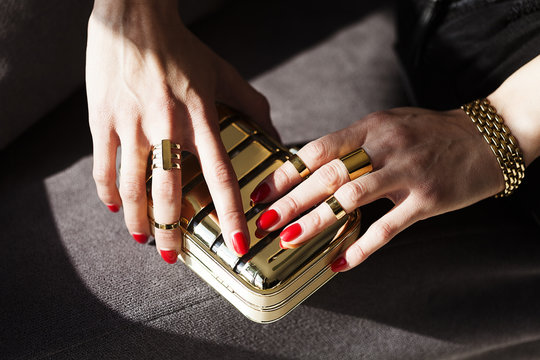 Elegant Woman's Hands on Golden Purse