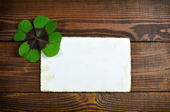 Lucky clover and blank greeting card on wooden background