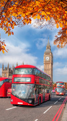 Obraz na płótnie Canvas Buses with autumn leaves against Big Ben in London, England, UK