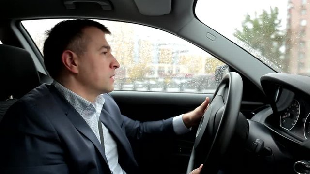 Respectable, responsible man driving car. Raining day. Dangerous road. The man in a suit. the man holds the steering wheel. Close up