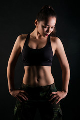 Fototapeta na wymiar Athletic girl in sport top on black studio background.