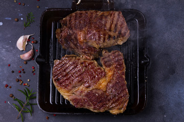 Hot Grilled beef steak with smoke on dark background