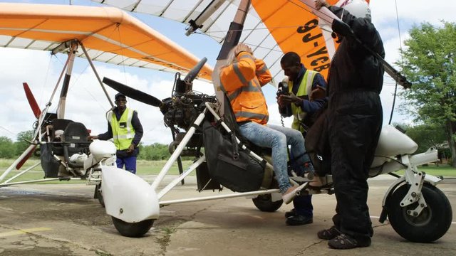 Excited woman disembarks from microlight aircraft after sightseeing flight