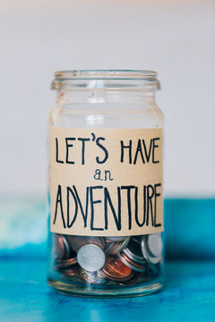 Money saving in jar with label saying
'let's have an adventure'