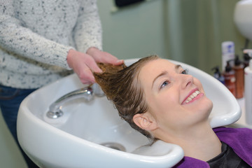 Obraz na płótnie Canvas happy woman is getting a hairwash by a hairdresser