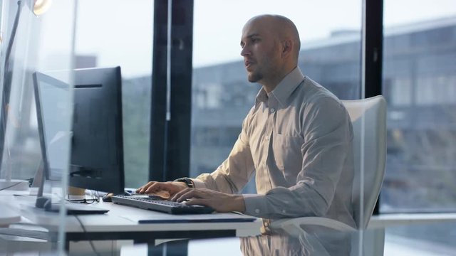 Frustrated Businessman  in glass modern office with large windows, working at his desk late at night and getting fed up with