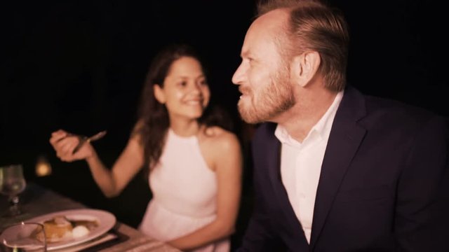  Woman feeding her partner during romantic meal at outdoor restaurant table