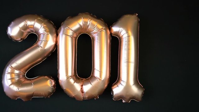 Happy 2018 gold New Year Balloons with glitter stars on black background, time lapse.