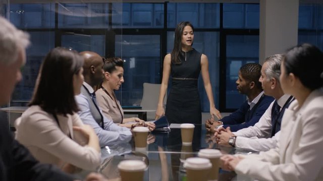  Businesswoman giving presentation to colleagues in late meeting