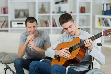 Man in wheelchair playing guitar, friend singing