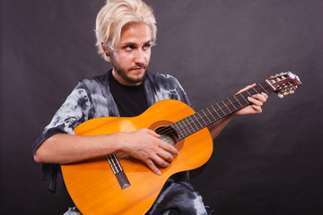 Blonde man playing acoustic guitar