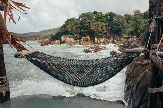 A net hammock on a cliff being splashed by the oceans waves