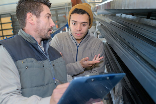 male engineer with apprentice checking stock levels