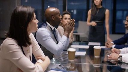  Businesswoman giving presentation to colleagues in late meeting