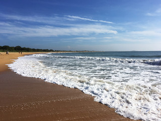 View of the coast line with waves crashing on the beach on a sunny day