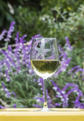 Glass of white wine outside with purple flowers in background