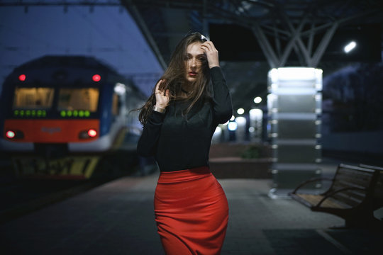 Beautiful young elegant woman traveler waiting for train at evening train station