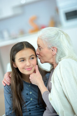 Obraz na płótnie Canvas smiling granddaugther embrace her grandmother at home