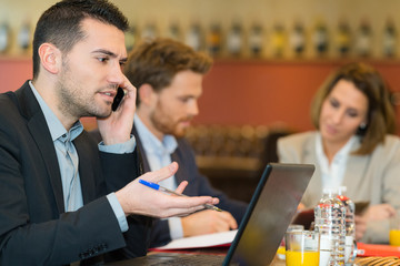 businessman with laptop and cellphone in cafe