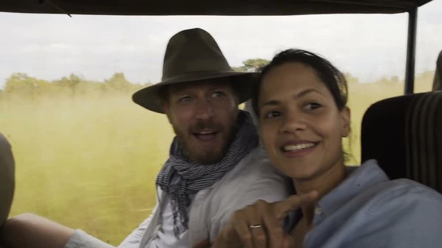  Couple in safari vehicle traveling through national park in Zambia, Africa