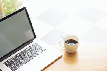 Laptop  and coffee on wooden table .