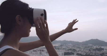 Woman looking though virtual reality device on the roof top