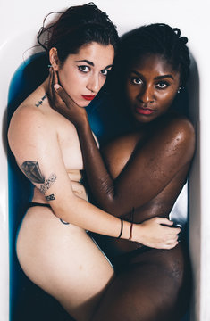 Two beautiful tattooed women cuddling in a bath