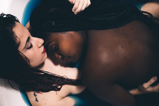 Two beautiful tattooed women cuddling in a bath