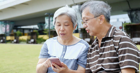 Retired couple using mobile phone together
