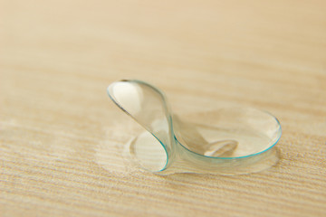Contact lenses for eyes with drops of solution on a wooden table