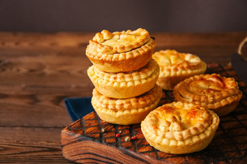 Mini meat pies from flaky dough on a wooden board over wooden background. - 177495140