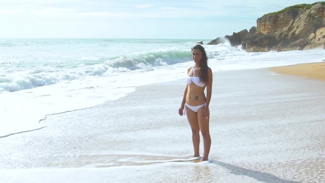 Slow motion of beautiful woman alone in an amazing and unspoiled beach in the spain coast