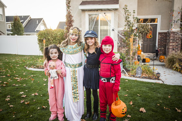 Group of kids dressed in Halloween costumes going trick or treating outdoors in October in a...