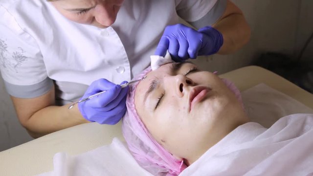 beautician squeezing pimple blackheads for young wonan in beauty salon. facial skin care