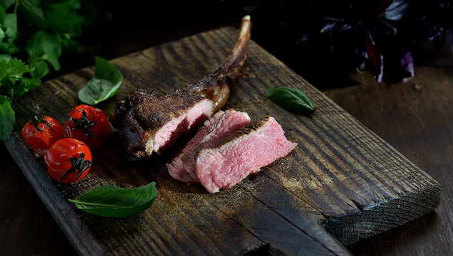 grilled lamb steak with  tomatoes on a wooden background