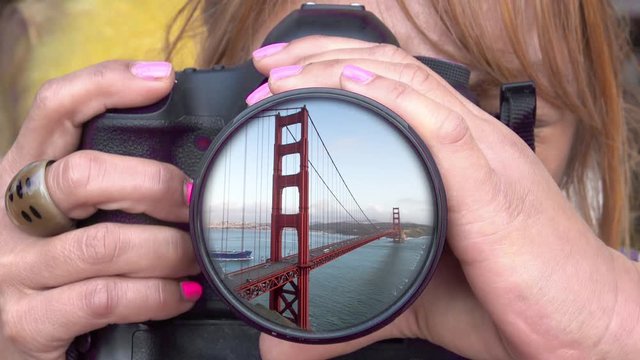 Female Photographer taking a Picture. Golden Gate Bridge reflecting in the Lens.