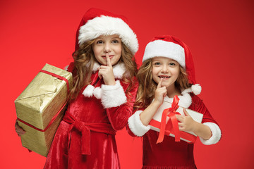 Two happy girls in santa claus hats with gift boxes at studio