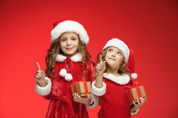 Two happy girls in santa claus hats with gift boxes at studio