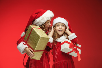 Two happy girls in santa claus hats with gift boxes at studio