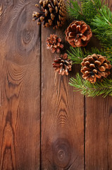 Fototapeta premium Christmas background. Fir tree branches and cones on a wooden backdrop. Copy space. Top view.