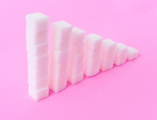 High to low stacks of sugar cubes with pink background, health care diet concept