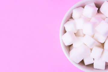 Closeup sugar cubes on bowl with pink background, health care concept