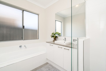 Interior of a white, light coloured bathroom in a modern Australian home.