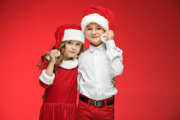 Two happy boy and girl in santa claus hats with gift boxes at studio