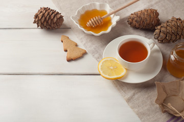 Cup of tea with lemon and honey on white wooden background, cozy home still life, lazy breakfast weekend, copy space