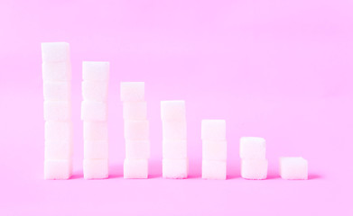 High to low stacks of sugar cubes with pink background, health care diet concept