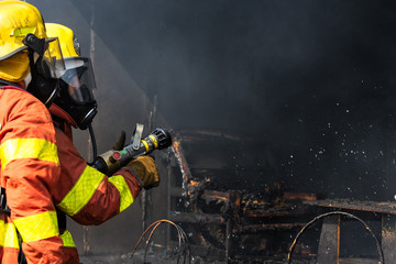 Fototapeta premium two firefighters with high pressure nozzle surround with dark smoke and copy space