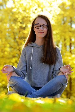 Girl doing yoga in autumn park.