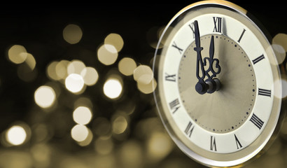 Fototapeta na wymiar Old clock at New Year midnight with holiday lights.